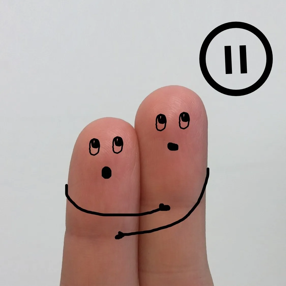 Dos dedos con caras y brazos dibujados simulan un abrazo junto a un símbolo de pausa.