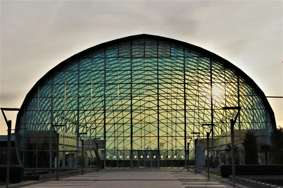 Sonnenlicht fällt durch die geschwungene Fassade eines Glasgebäudes.