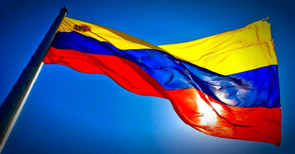 Die venezolanische Flagge weht vor blauem Himmel.