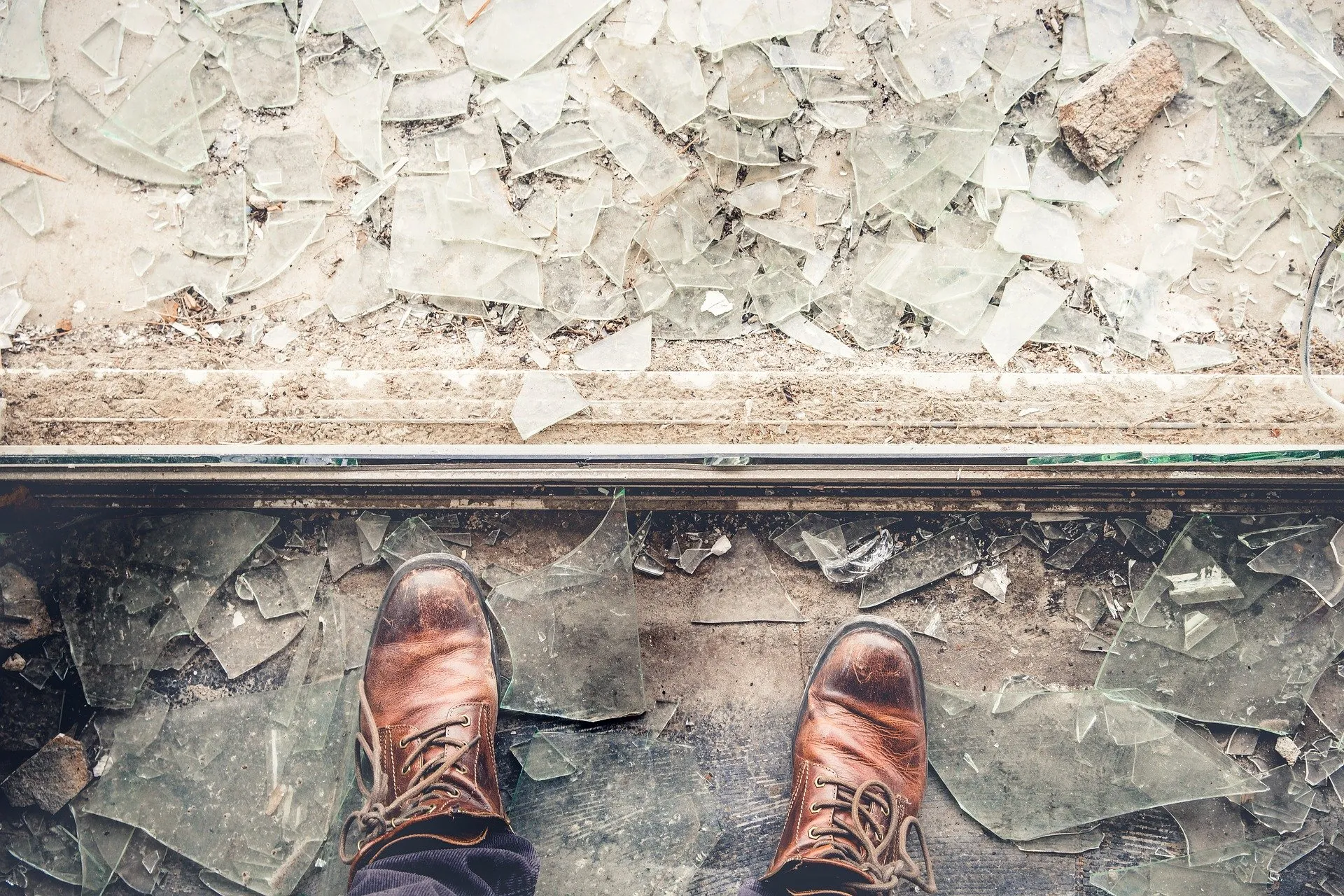 Shoes in front of a floor covered in broken glass.
