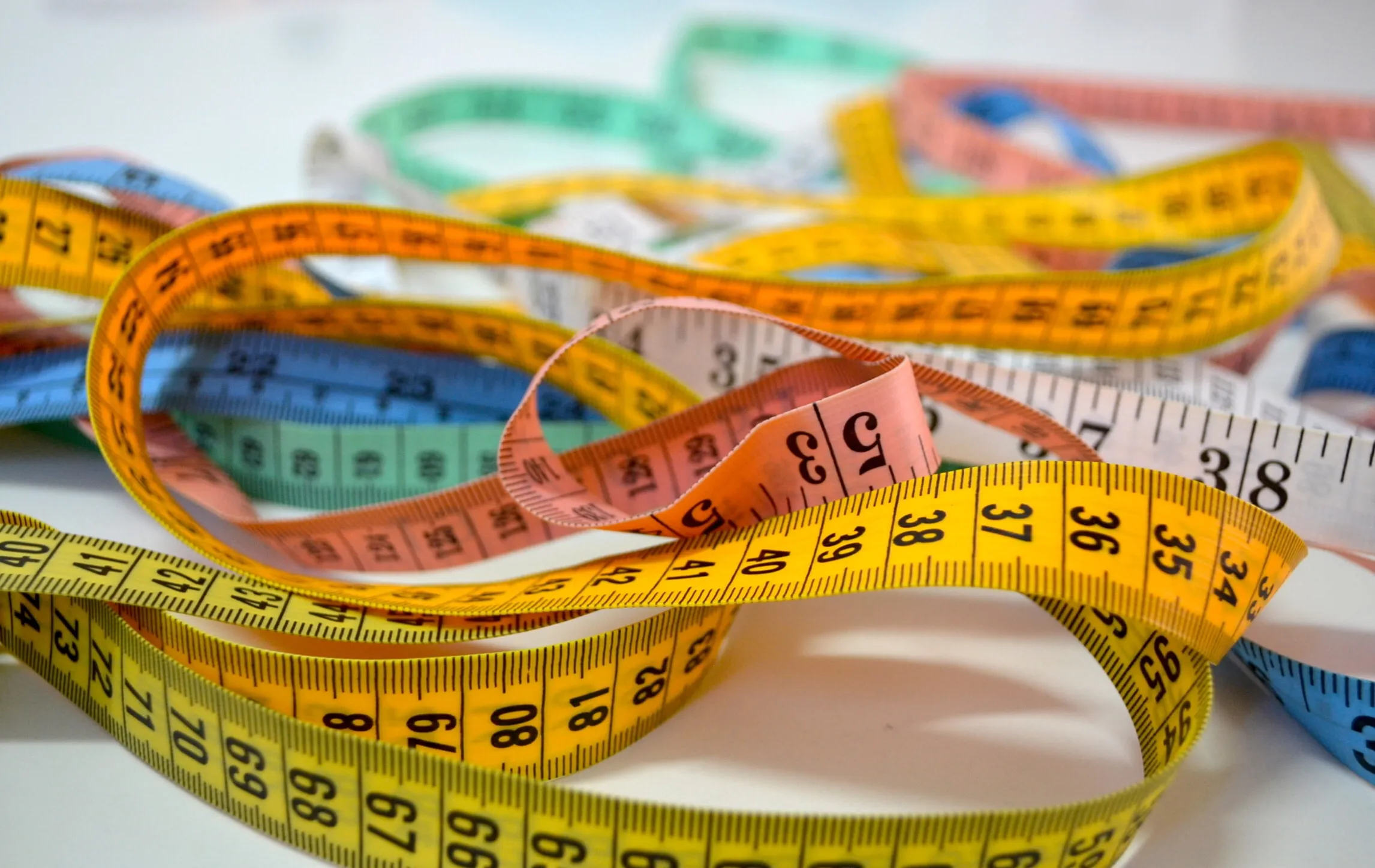 Several colourful measuring tapes intertwined.