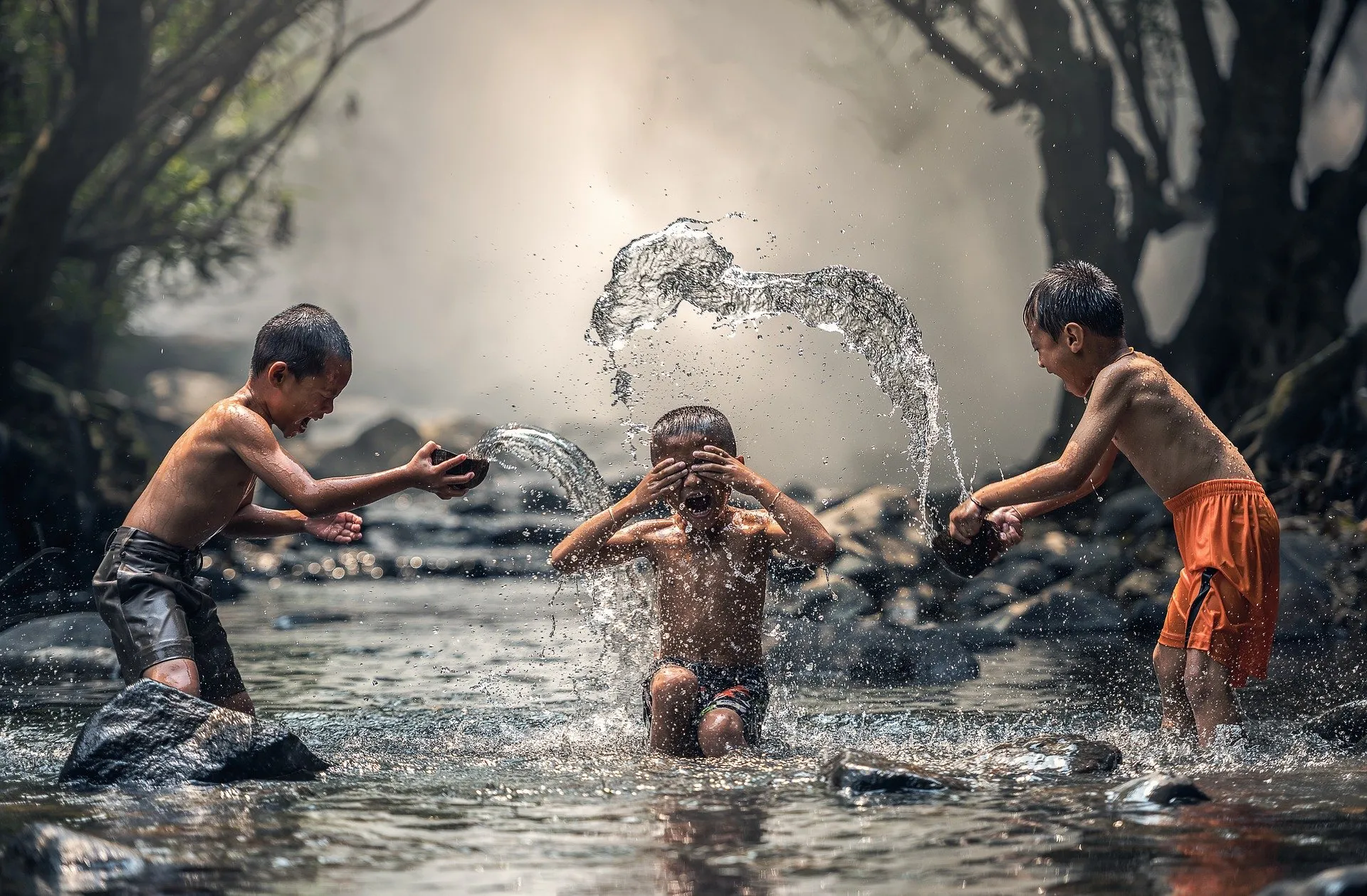 Varios niños juegan salpicándose agua en un río.