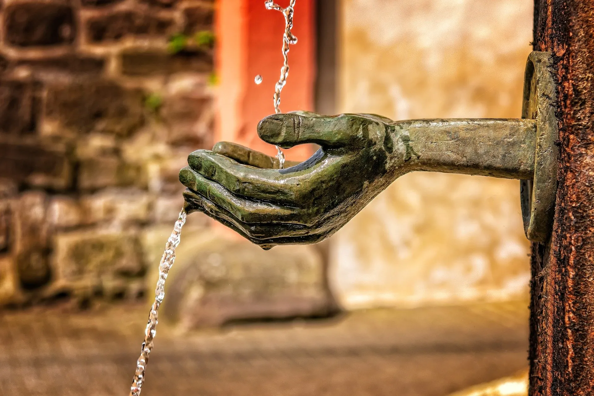 Wasser fließt aus einem Brunnen in Form einer offenen Hand.