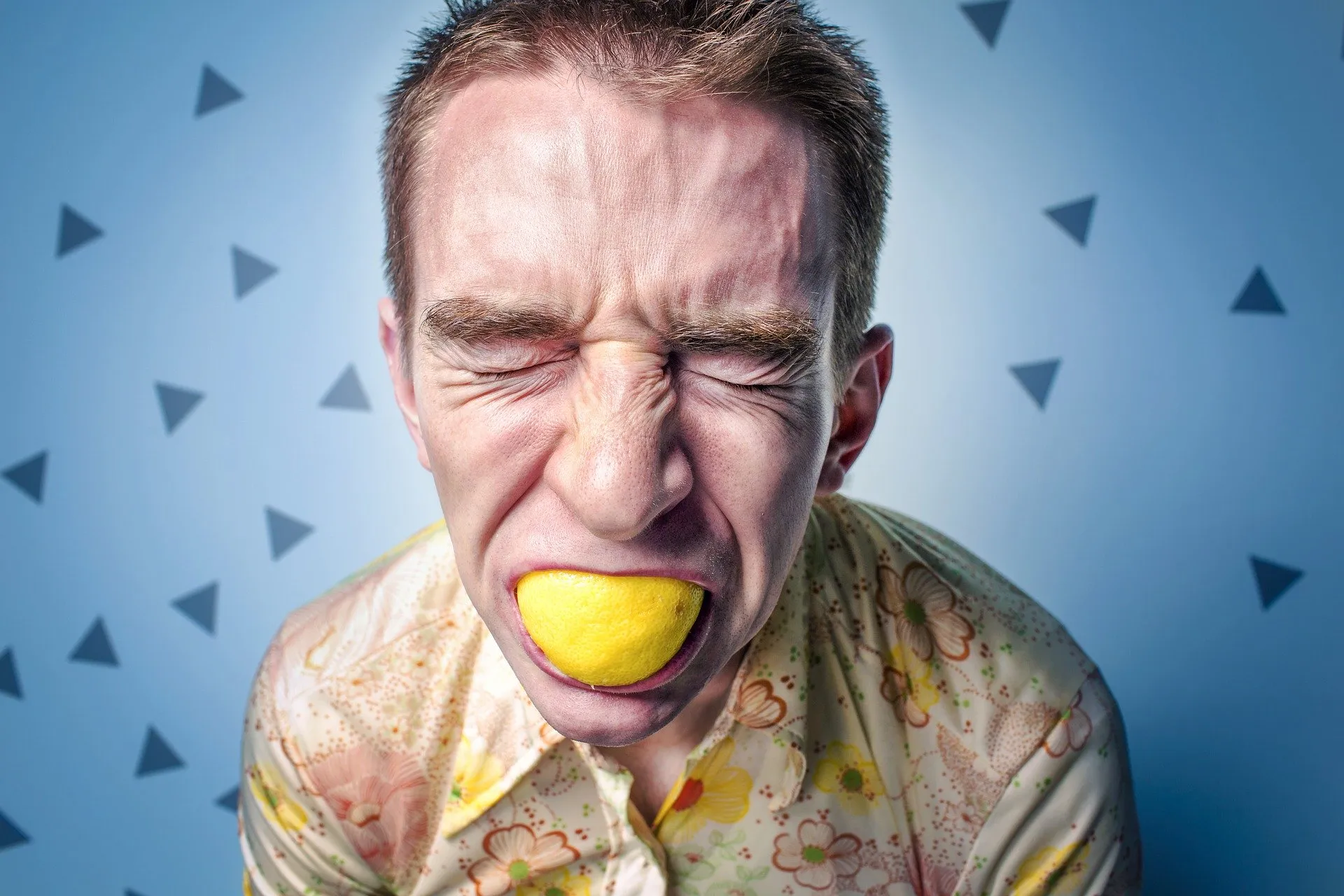 Un hombre con los ojos cerrados sostiene un limón entre los dientes.